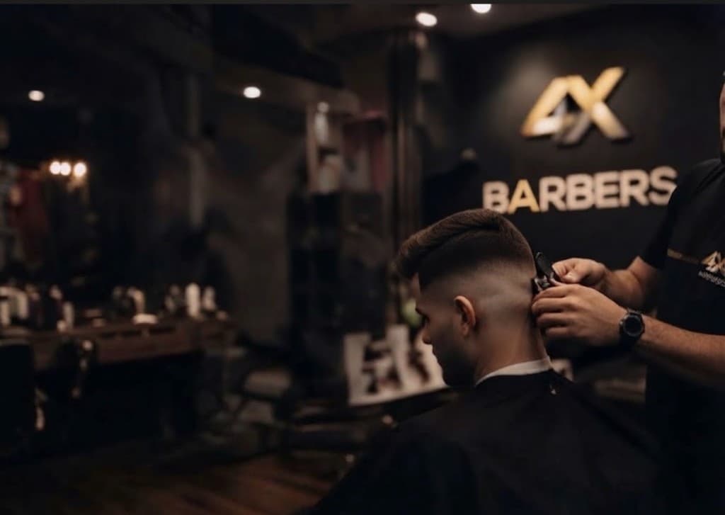 A barber cutting a client's hair at 4X Barbers